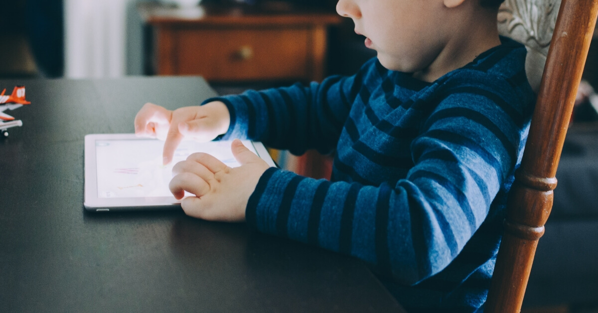 young boy playing on iPad screen