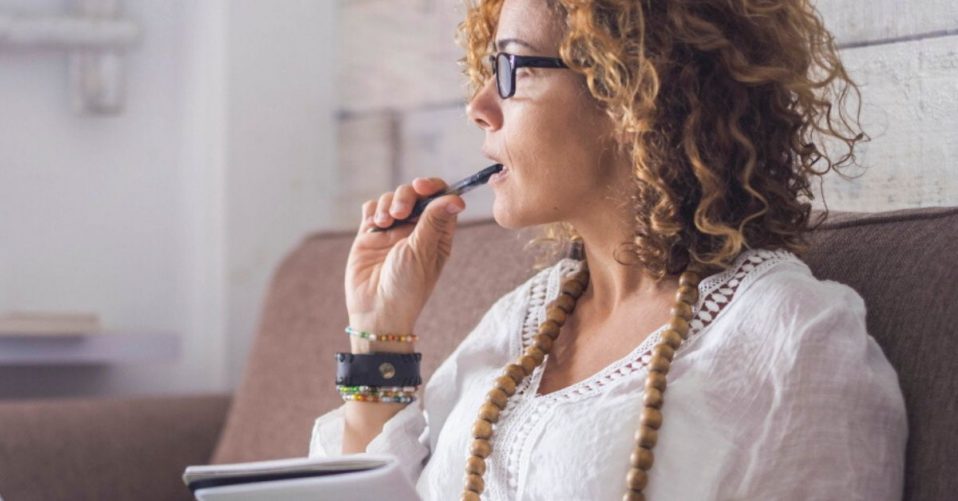 seeing opportunity in change - a photo of a woman chewing a pencil with notepad in her lap, gazing into the distance